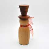A wooden snowman decoration with a dark brown top hat, a light natural wood body, red and green decorative buttons, and a red glittery scarf, styled with warm fairy lights, gold beads, and holiday ornaments.