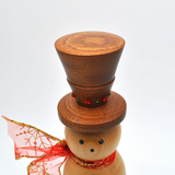 A wooden snowman figurine with a brown top hat decorated with small red and green rhinestones, a light natural wood face and body, and a red sheer scarf with gold glitter.