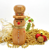 A wooden snowman Christmas decoration with an Olive wood hat, red nose, and gold ribbon, surrounded by gold beads, red ornaments, and a clear glass ornament on a white background.